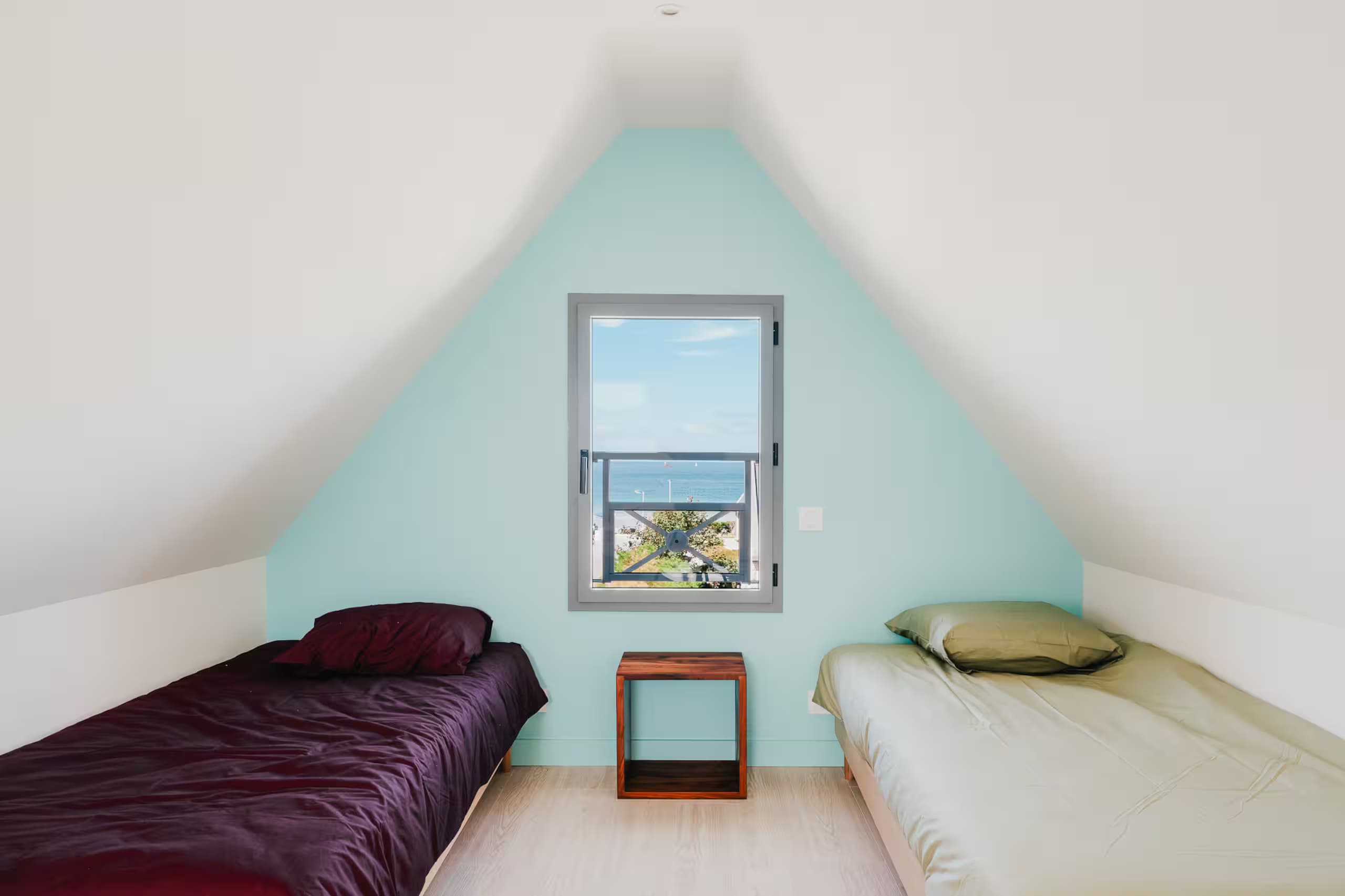 Chambre mansardée avec deux lits simples et vue sur la mer
