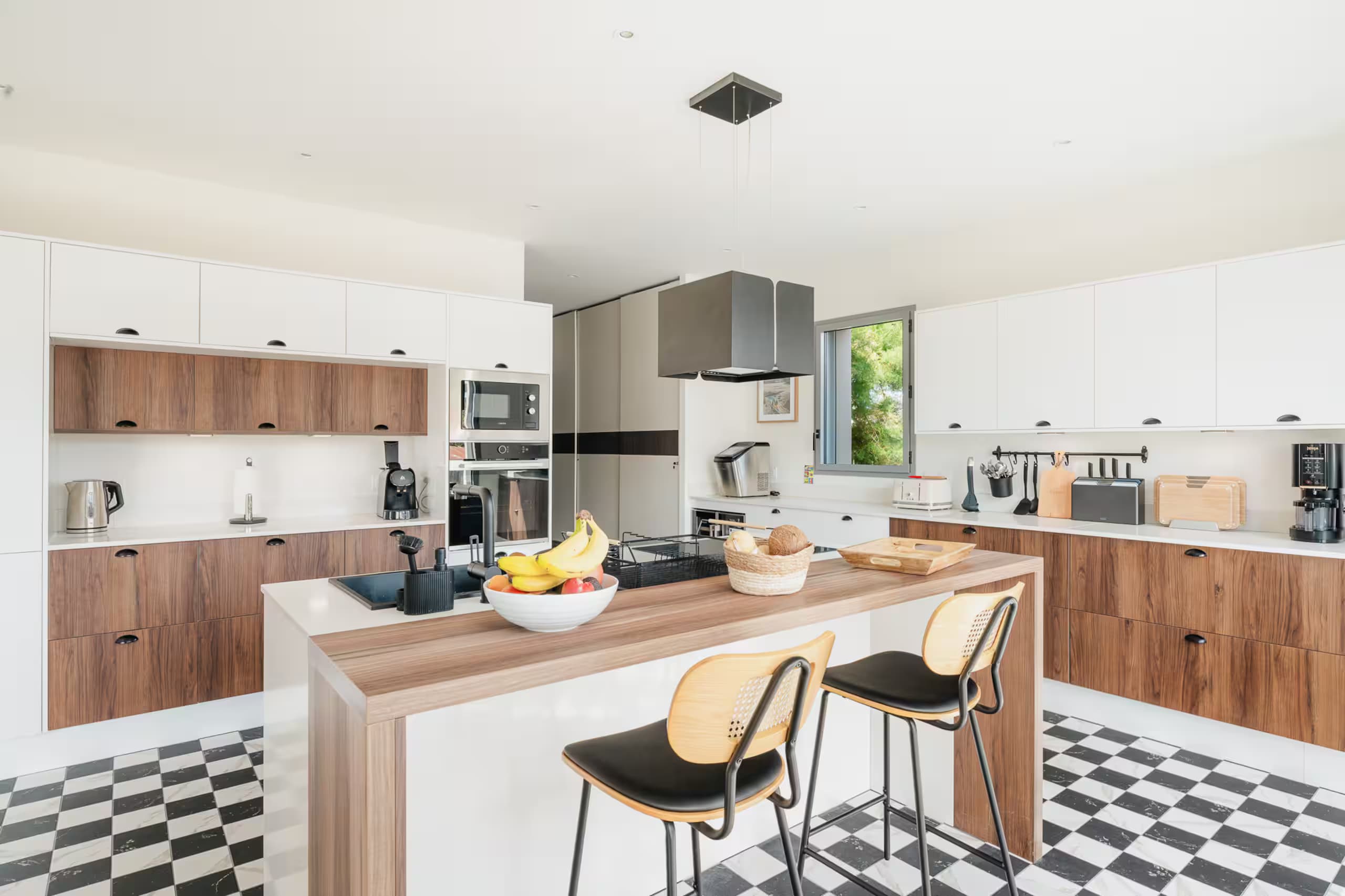 Cuisine ouverte avec îlot central, tabourets et sol en damier