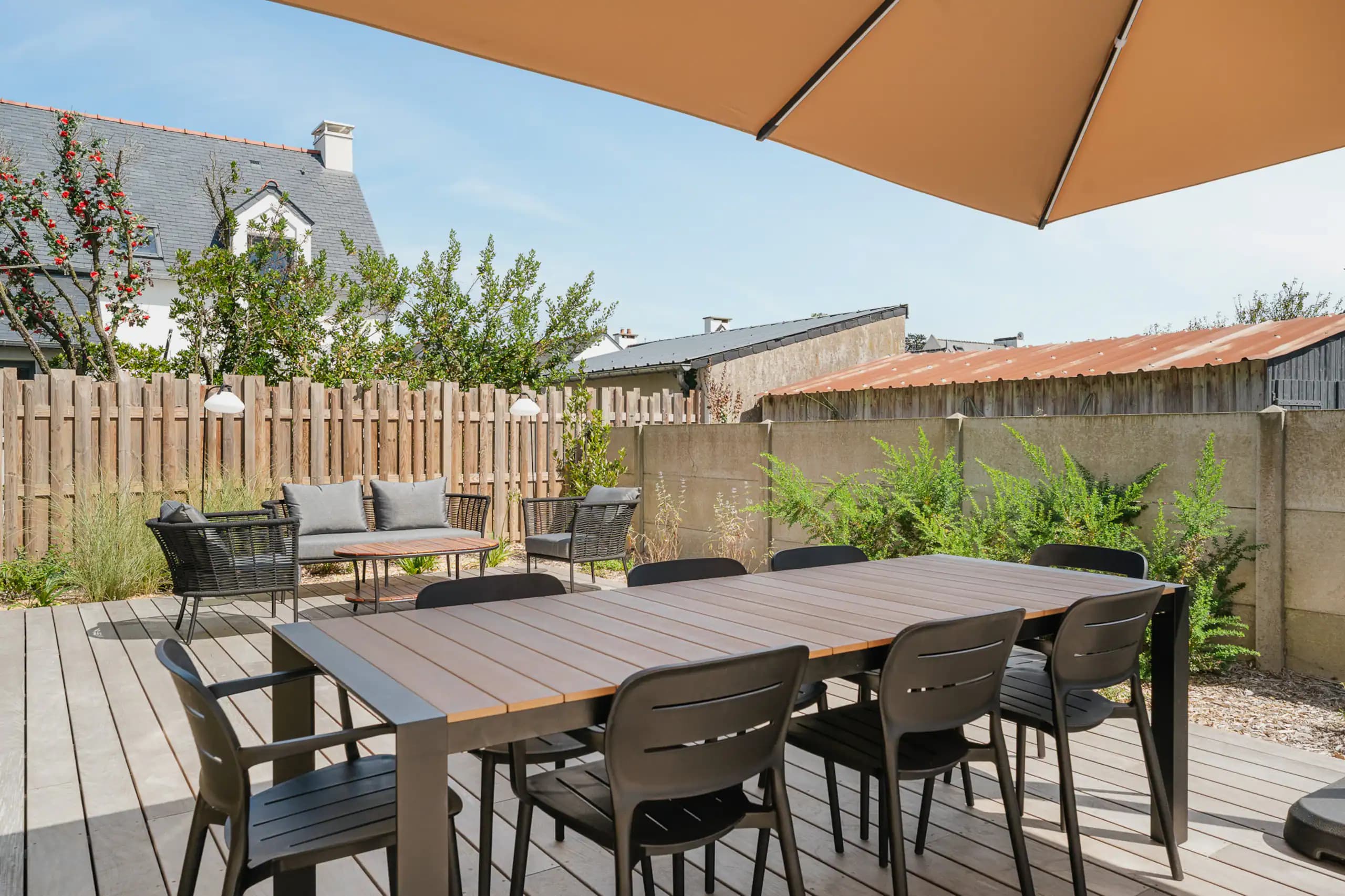 Table de jardin pour huit personnes sous un parasol beige