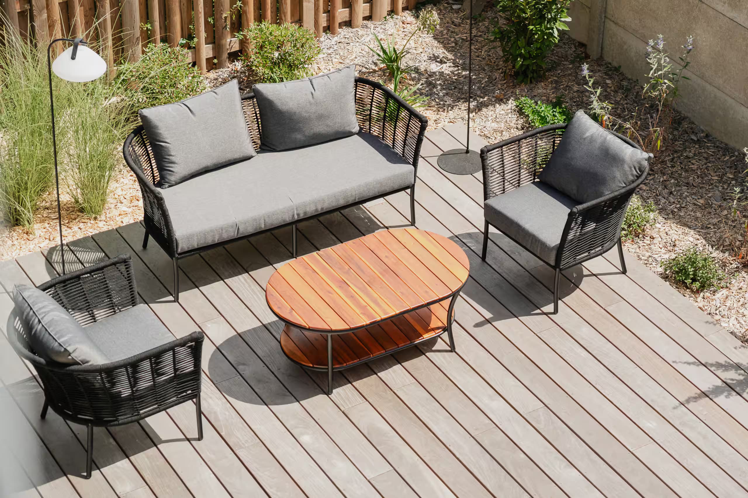 Canapé et fauteuils extérieurs autour d’une table basse en bois