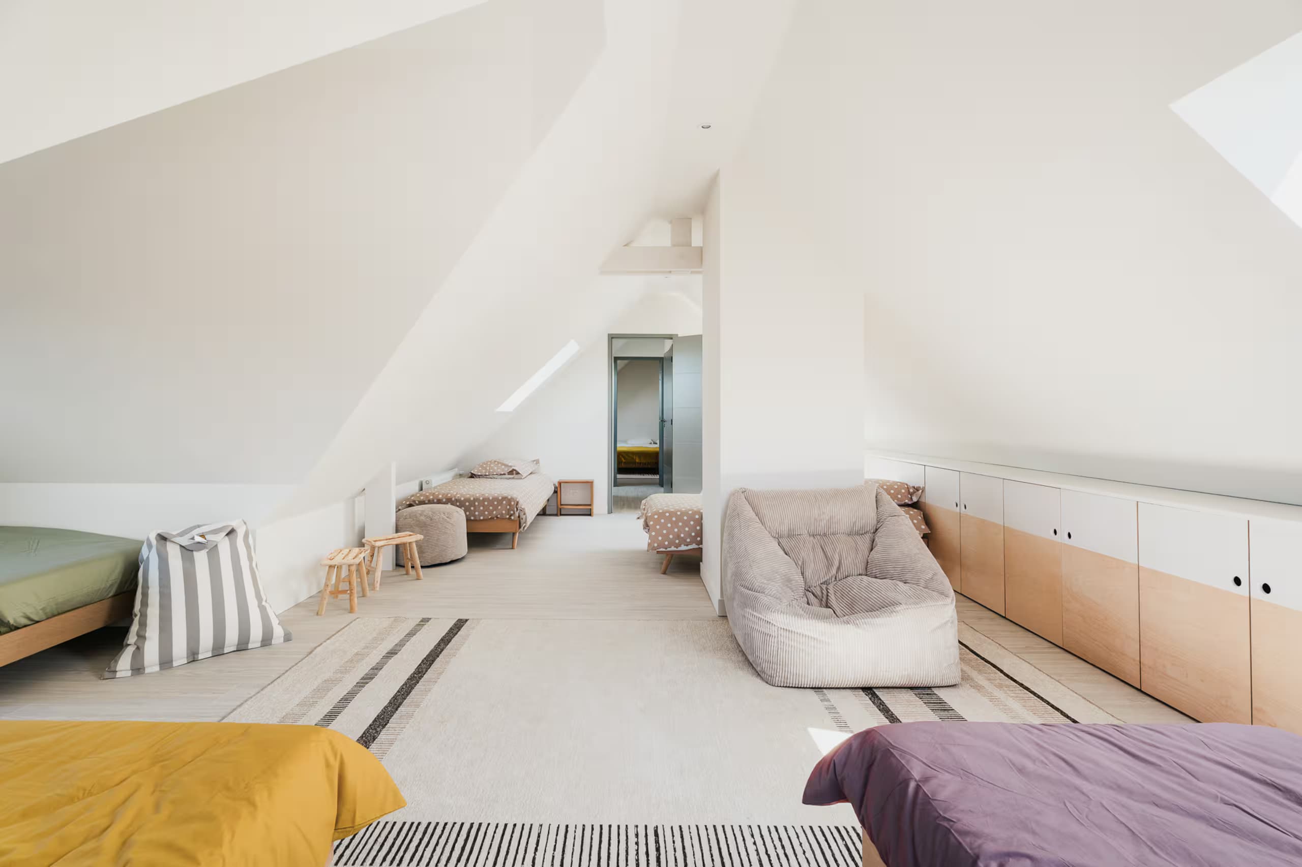 Combles avec matelas, poufs et rangements