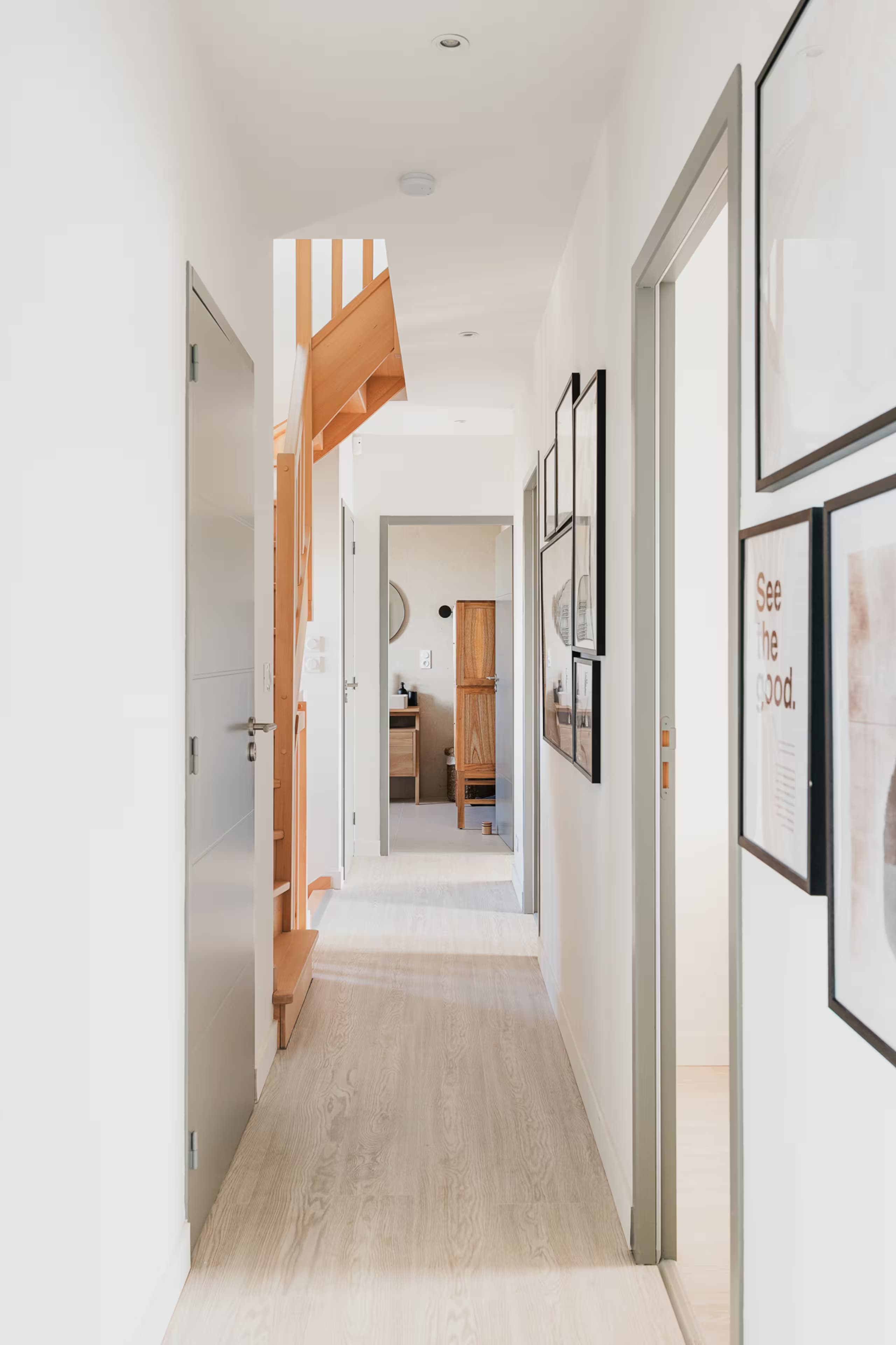 Couloir clair menant aux chambres, cadres au mur
