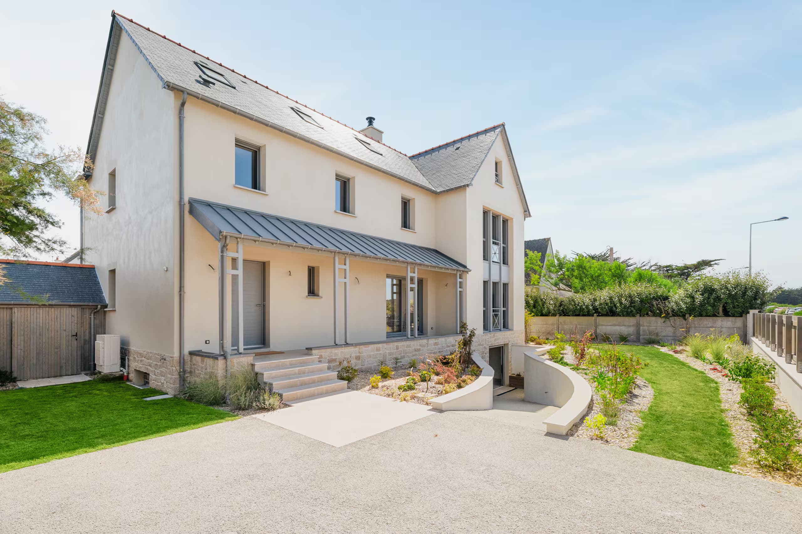 Façade avant de la villa en pierre et enduit clair, toit d’ardoise